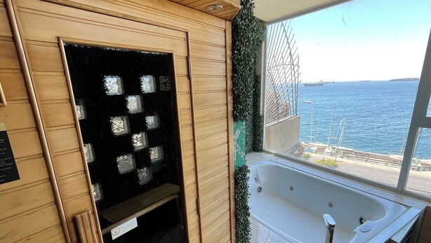 A spa area with a wooden cabinet, a black glass door, a white bathtub, and a view of the sea. - Asian Style Home with the Best View in Viña! (viña del mar)
