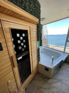 A spa area with a wooden cabinet, a black glass door, a white bathtub, and a view of the sea. - Asian Style Home with the Best View in Viña! (viña del mar)