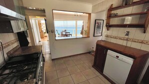 A kitchen with a gas stove, a dishwasher, and a window overlooking a balcony. - Asian Style Home with the Best View in Viña! (viña del mar)