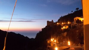 A mountainous landscape with a lit building at the top, possibly a hotel, and a road with vehicles. - Brand new apartment adjacent to the famous Vitelli bar from the film IL PADRINO. (Savoca)