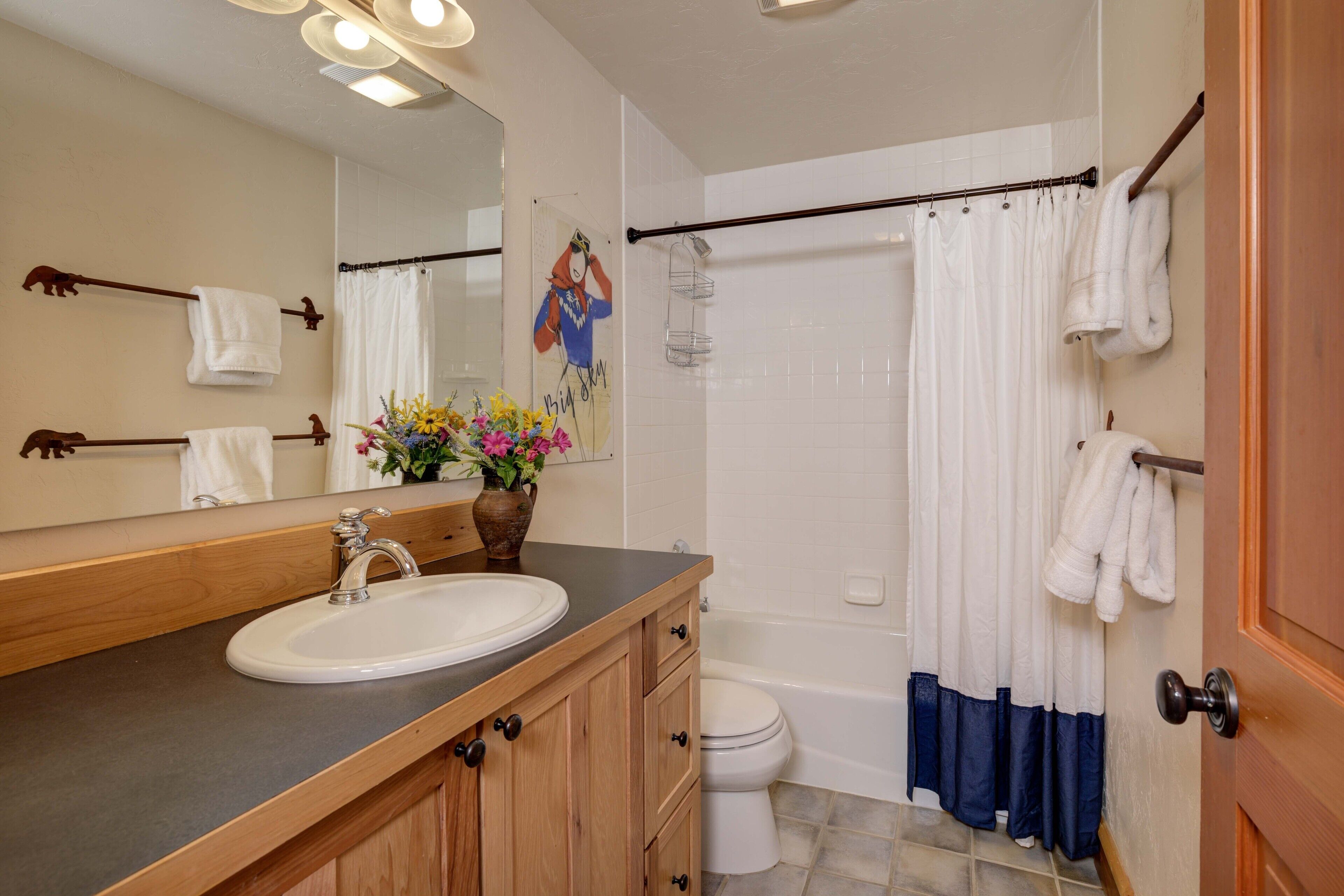 Une salle de bain équipée d’un lavabo, d’un miroir, de toilettes et d’un rideau de douche.