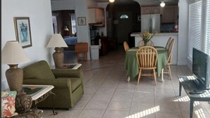 Uma sala de estar ampla com um sofá, uma mesa de centro e uma mesa de jantar para quatro pessoas.