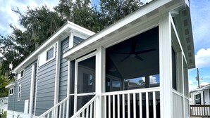 A small, single-story building with a covered porch and a staircase leading to a deck.