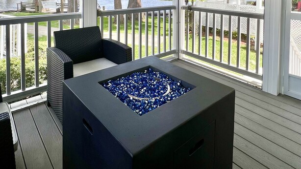 A covered outdoor area with a fire pit, seating, and a view of the water and trees.