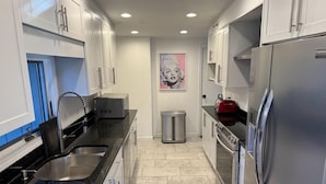 A modern kitchen with white cabinets, stainless steel appliances, and a tiled floor.