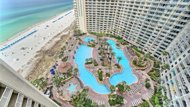 A high-rise hotel with a pool area, beach access, and a view of the ocean.