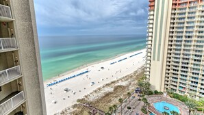 A high-rise hotel with a beach view, a swimming pool, and a sandy beach with umbrellas.