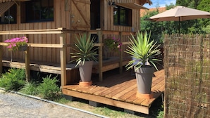 Une cabane en bois avec un porche, des plantes en pot et un espace extérieur abrité.
