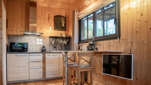 L’intérieur d’un chalet en bois comprend un coin cuisine équipé d’un four à micro-ondes, d’un évier et d’une table à manger avec des chaises.