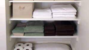 A closet with multiple storage boxes and shelves, containing folded clothes and toiletries. - Heron's Perch Efficiency Studio (Port Townsend)