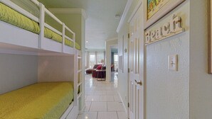 A hotel room with bunk beds, a dining area, and a hallway leading to a door labeled "Beach". - Beach Therapy at Maravilla by My Galveston Getaway (Galveston)