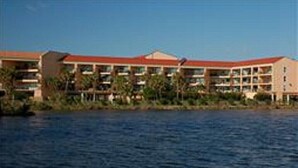 A hotel with multiple floors, a red roof, and a body of water in the foreground. - Beach Therapy at Maravilla by My Galveston Getaway (Galveston)