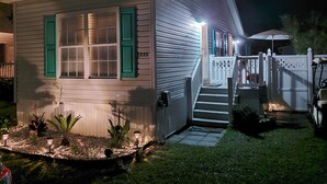A single-story house with a front porch, a visible number '1735' on the door, and a small garden area with plants and a pathway leading to the entrance. - CLEAN , Pet Friendly Beach House w/ golf cart and free beach parking (Surfside Beach)