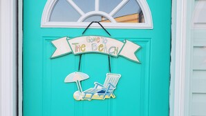 A turquoise door with a white-framed window, a sign reading "Gone to the Beach," and a beach chair and umbrella decoration. - CLEAN , Pet Friendly Beach House w/ golf cart and free beach parking (Surfside Beach)