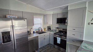 A compact kitchen with a stainless steel refrigerator, a microwave, a stove, and a sink. - CLEAN , Pet Friendly Beach House w/ golf cart and free beach parking (Surfside Beach)