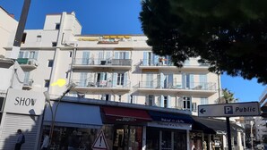 A multi-story building with balconies, a 'Show' sign, and a 'Swatch' store at street level. - Studio in the center of Juan-les-pins (Antibes)