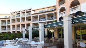 Un cortile alberghiero con posti a sedere all'aperto, diversi balconi e una zona pranzo coperta.