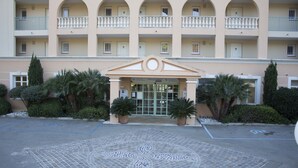 L'ingresso di un hotel con pavimento piastrellato, piante in vaso e un edificio a più piani con balconi.