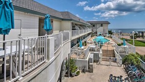 Et hotel med poolområde, udendørs siddepladser og udsigt til stranden.