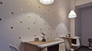 A modern dining area with a long table, white chairs, and pendant lighting. - Sea Fly Guest House (Fiumicino)