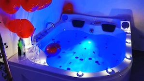 A hot tub with red heart-shaped balloons, a glass, and a bottle. - Sea Fly Guest House (Fiumicino)