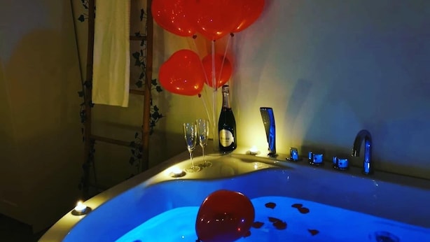 A bathtub with red balloons, a bottle, and glasses on a counter. - Sea Fly Guest House (Fiumicino)
