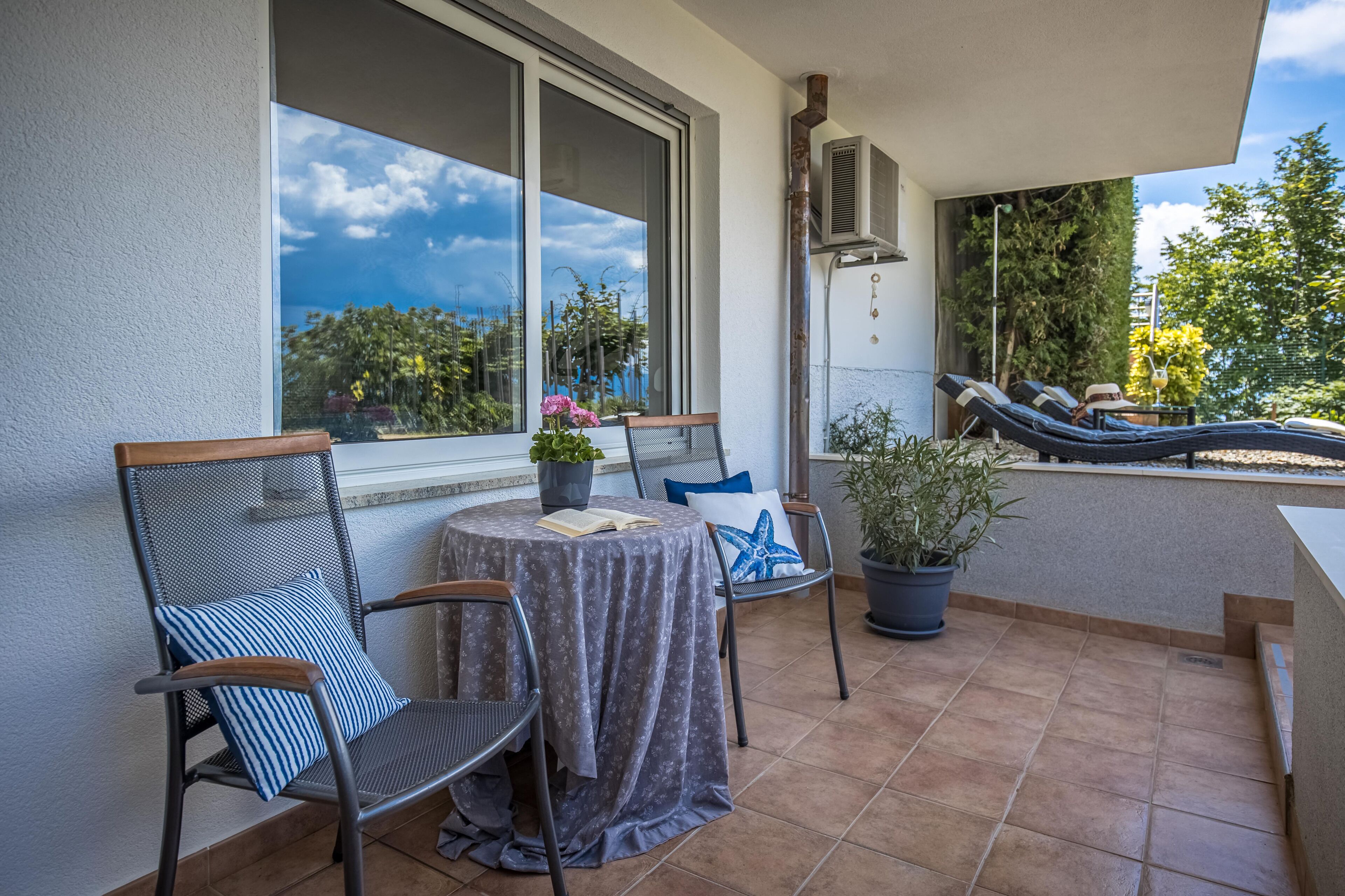 Eine Terrasse mit Tisch, Stühlen und einer Lounge, die auf Bäume und Himmel blickt.