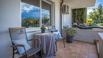 Eine Terrasse mit Tisch, Stühlen und einer Lounge, die auf Bäume und Himmel blickt.