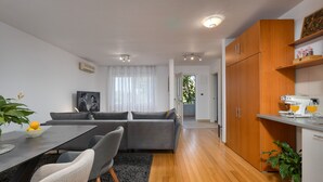Et moderne køkken med træskabe, et spiseområde med bord og stole, og en stue med sofa.
