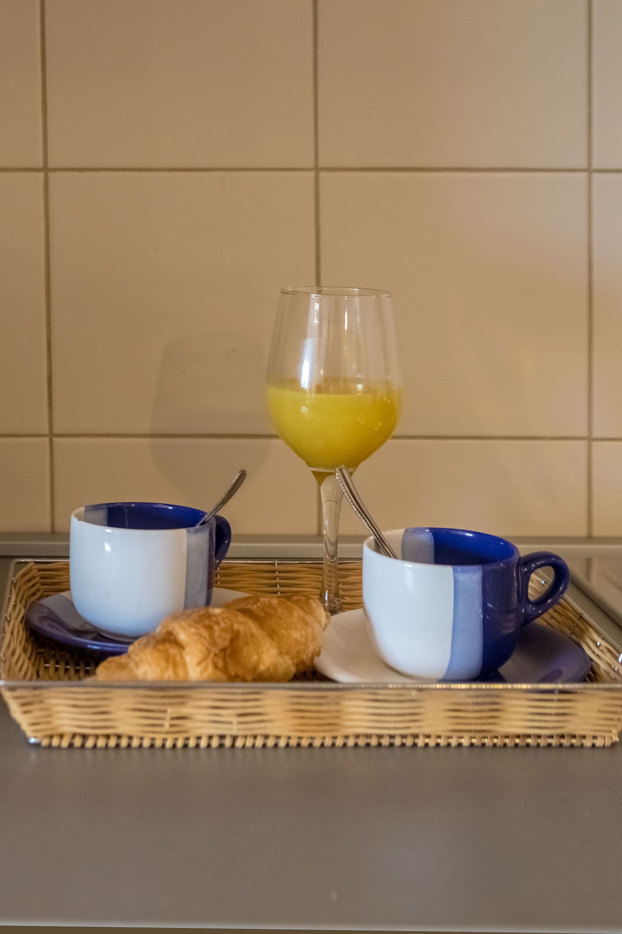 Ein Frühstücksbrett mit Croissants, zwei Kaffeetassen und einem Glas Orangensaft.