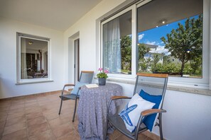 Een terras met een tafel en stoelen, een bloempot en uitzicht op een woonwijk.