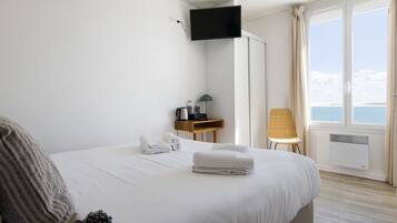 Une chambre d’hôtel avec un lit, un bureau avec une lampe, une chaise et un téléviseur fixé au mur.
