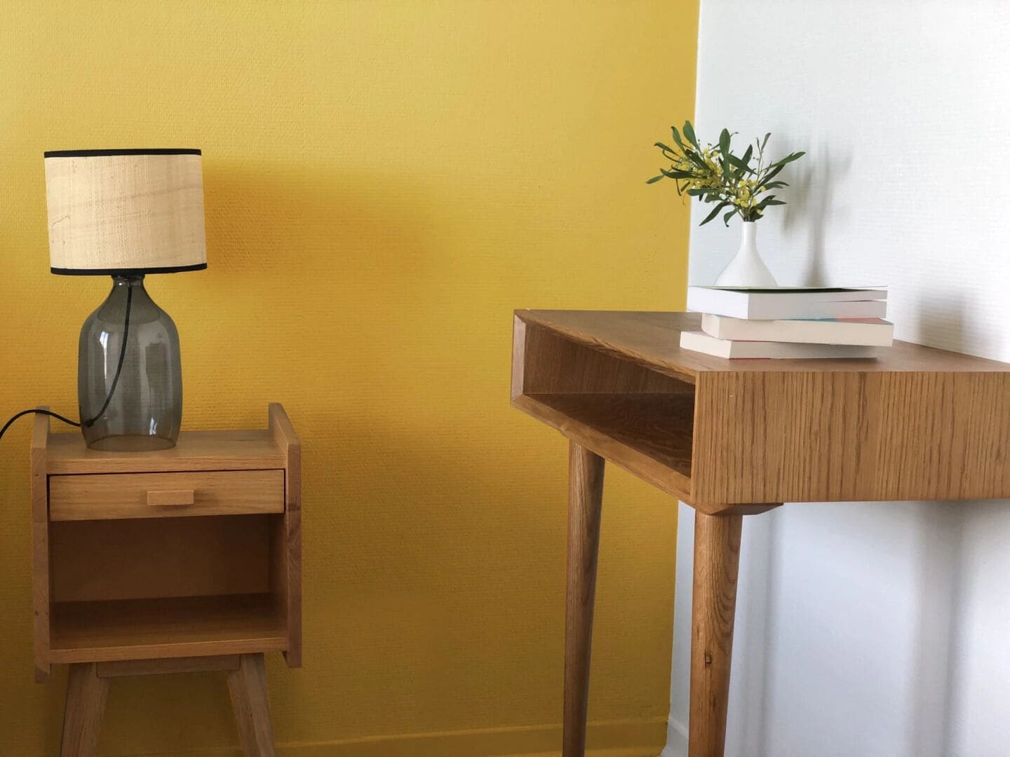 Un bureau en bois avec une lampe et un vase contenant des plantes.