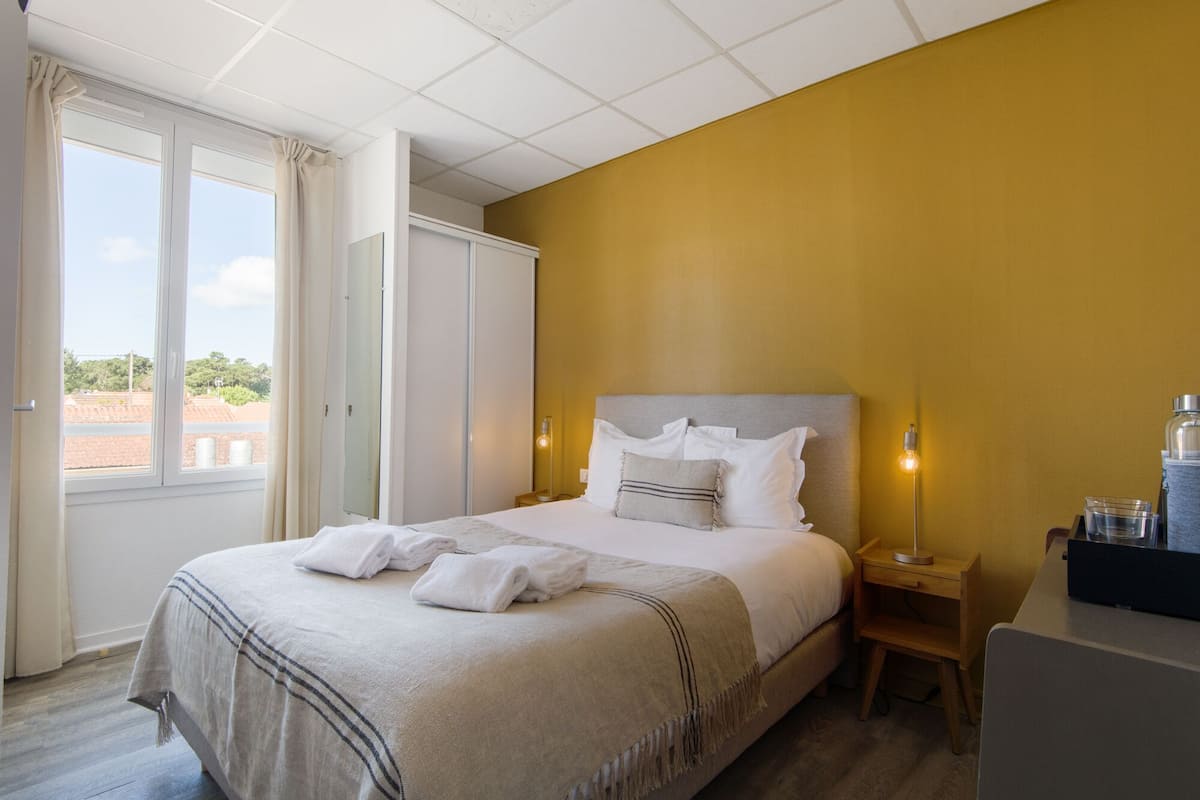 A hotel room with a bed, bedside tables, a wardrobe, and a view of the outside.