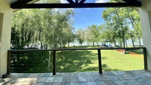 Une terrasse couverte donnant sur une pelouse et des arbres.