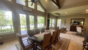Un espace repas comprenant une grande table et des chaises, un ventilateur de plafond et une vue sur l’extérieur.