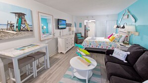 Una habitación con decoración playera, que incluye una cama, un escritorio y un sofá.