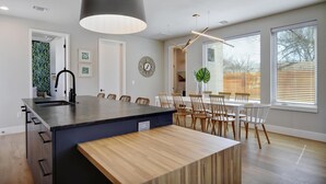 Una cocina moderna con una isla central, sillas de madera y una mesa de comedor.