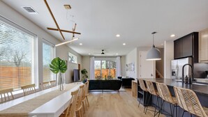 Una cocina moderna con una isla central, suelo de madera y un comedor con una mesa larga y sillas.