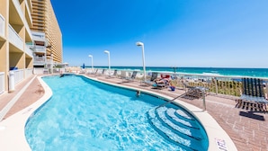 Une piscine offrant une vue dégagée sur l’océan, avec un immeuble de grande hauteur en arrière-plan.