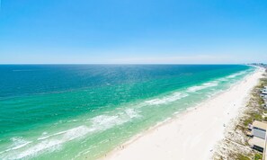 A coastal beach with clear turquoise waters and a sandy shore.