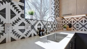Una cocina moderna con paredes de diseño geométrico, un ventanal grande y un lavamanos con grifo.