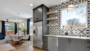 Una cocina moderna con armarios grises, un refrigerador de acero inoxidable y un salpicadero con diseño.