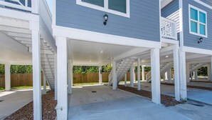 A two-story house with a covered patio area, a wooden fence in the background, and a clear sky. - Charming cabin with full kitchen! Unit 3/6 (San Leon)