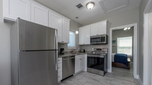 A modern kitchen with white cabinets, stainless steel appliances, and a view to the outside. - Charming cabin with full kitchen! Unit 3/6 (San Leon)
