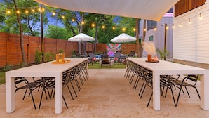 An outdoor patio with a long white table, black chairs, and two white umbrellas. - InstaWorthy Group Travel Retreat | 3.5 Miles to DT (Austin)
