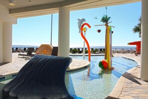 Ein Poolbereich mit Rutsche, Liegestühlen und Blick auf den Ozean.
