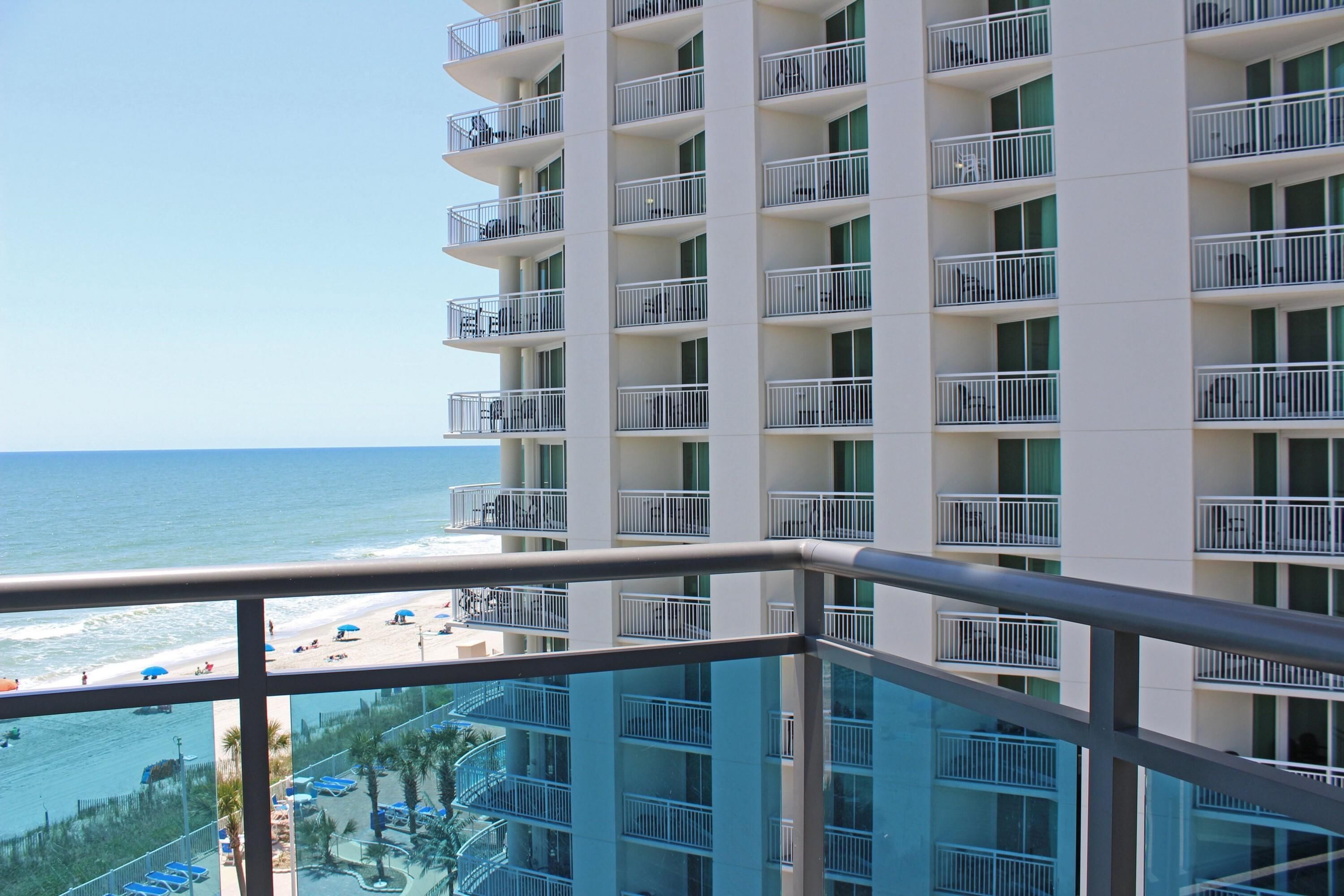 Ein Hochhaus-Hotel mit mehreren Balkonen mit Blick auf Strand und Poolbereich.