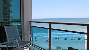 A balcony with a view of the beach, chairs, and a railing. - Oceans One by Palmetto Vacations (Myrtle Beach)