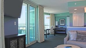 A hotel room with a balcony, a dining area, a sofa, and a round table. - Oceans One by Palmetto Vacations (Myrtle Beach)